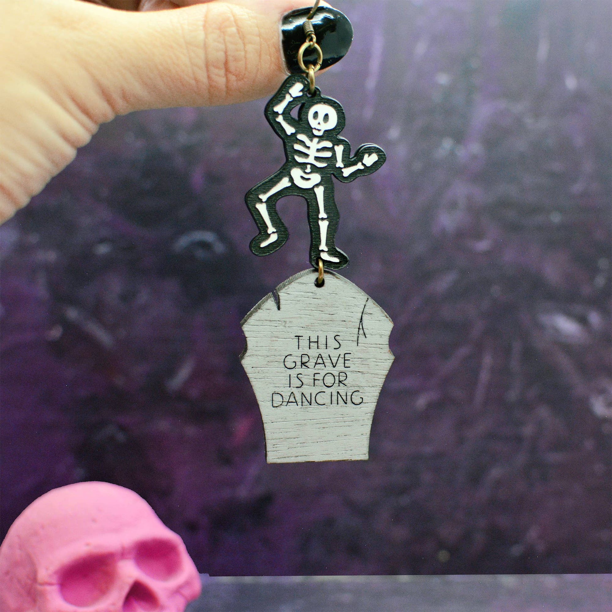 Statement earrings with a funny message, featuring a gravestone and skeleton for Halloween. This design depicts a skeleton dancing on it's own grave. The gravestone reads "this grave is for dancing".